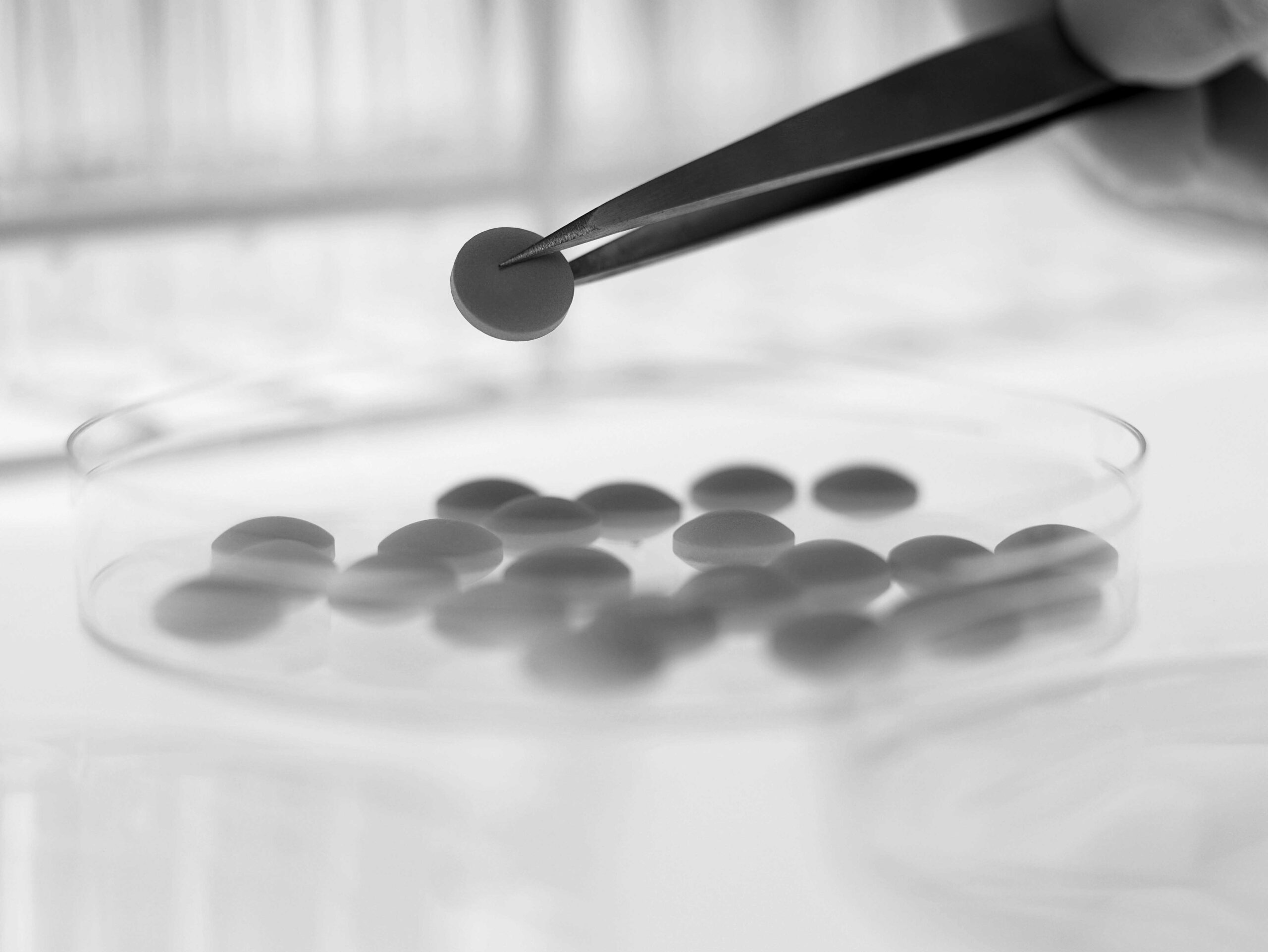 Scientist lifting pill from petri dish with tweezers. Image shot 2009. Exact date unknown.